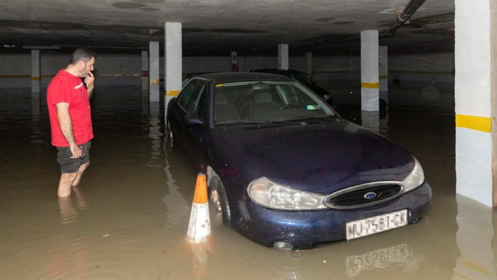 Un hombre observa su coche que ha quedado atrapado en el garaje inundado de su vivienda, tras las fuertes lluvias que han caído en las últimas horas en el barrio de San Ginés de Cartagena