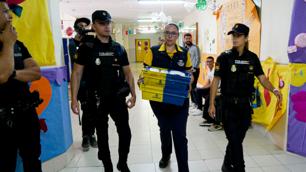 Dispositivo de Seguridad en Colegio León Solá de Melilla en el que varios agentes escoltan a la funcionaria de Correos a la mesa electoral para entregar los votos por correo