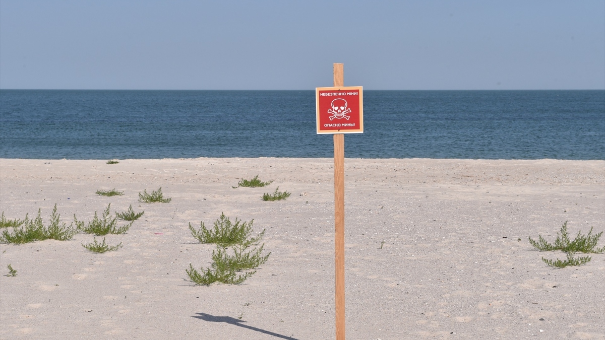 El siniestro cartel rojo de calavera y huesos cruzados advierte ''Peligro de minas'' en una playa vacía en la ciudad portuaria de Odessa, en Ucrania, en el Mar Negro.