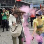 Una manifestante arroja pintura en polvo a una asistente a The District