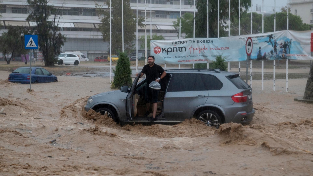 Un hombre intenta salir de su coche en una carretera inundada en Volos (Grecia)
