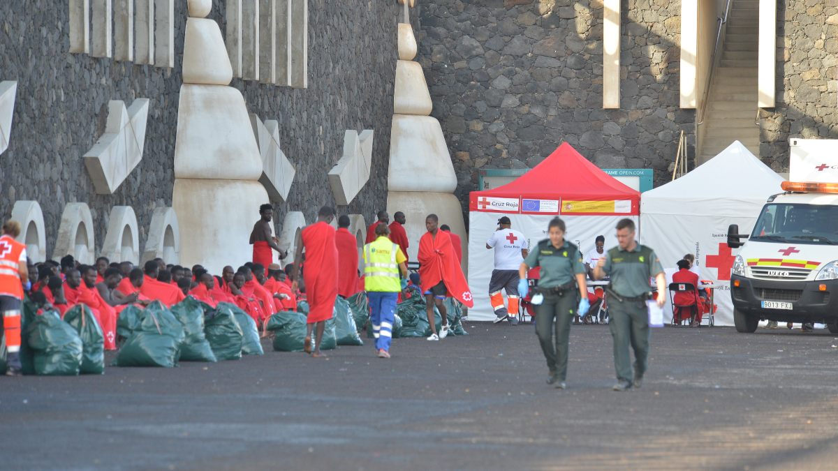 Dos agentes de la Guardia Civil junto a un grupo de inmigrantes recién llegado a El Hierro (Canarias)