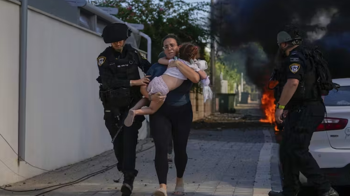 Agentes de policía israelíes evacuan a una mujer y un niño de un lugar alcanzado por un cohete en Ashkelon, sur de Israel