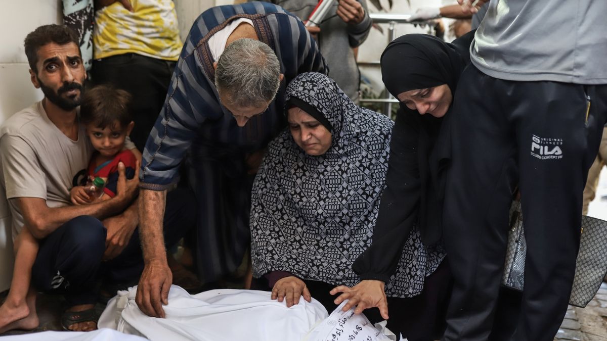 Una grupo de unas personas llora a un muerto por el ataque al hospital Al-Ahli de Gaza