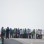 Inmigrantes hacen cola para subir al barco en el que serán trasladados desde la isla de El Hierro