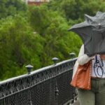 Dificultades para caminar por el Puente de Triana debido al viento y la lluvia
