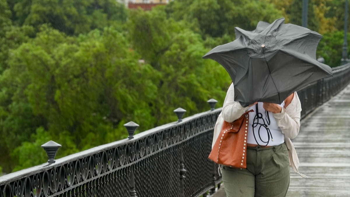 Dificultades para caminar por el Puente de Triana debido al viento y la lluvia