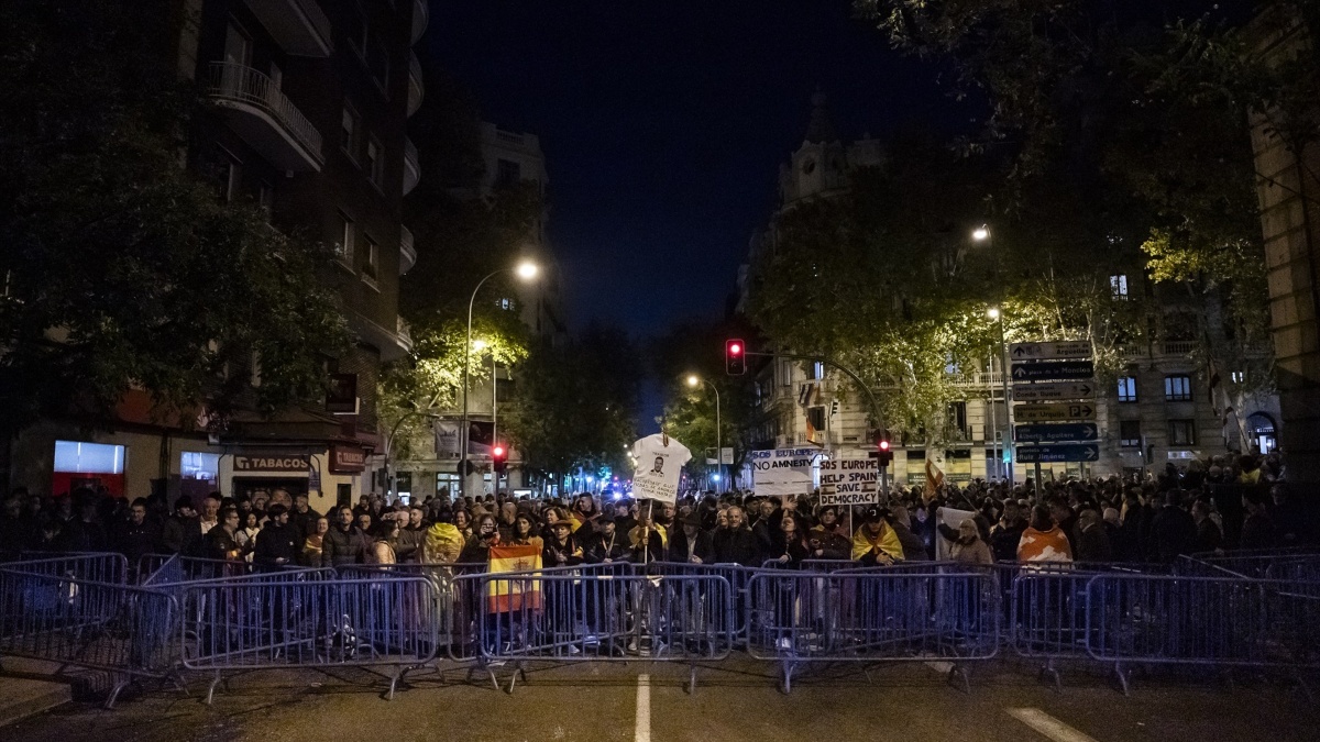 Decenas de personas tras las vallas con carteles y banderas de España, durante una manifestación contra la amnistía frente a la sede del PSOE en Ferraz