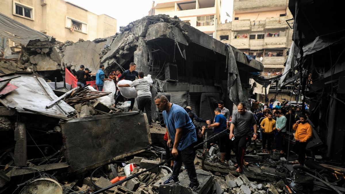 Gente recoge enseres entre las ruinas de un edificio bombardeado en Gaza