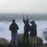 Tres jóvenes miran el mar embravecido en A Coruña