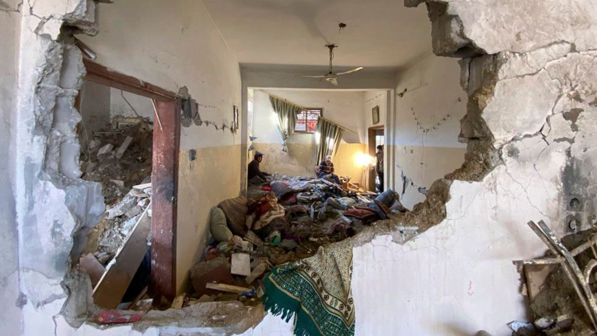 Dos gazatíes en su casa tras ser bombardeada