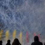 Varias personas observan el humo de colores durante la primera mascletà madrileña