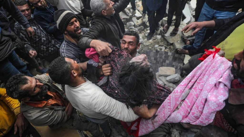 Varios hombres retiran el cadáver de una niña entre los escombros tras los bombardeos de Israel