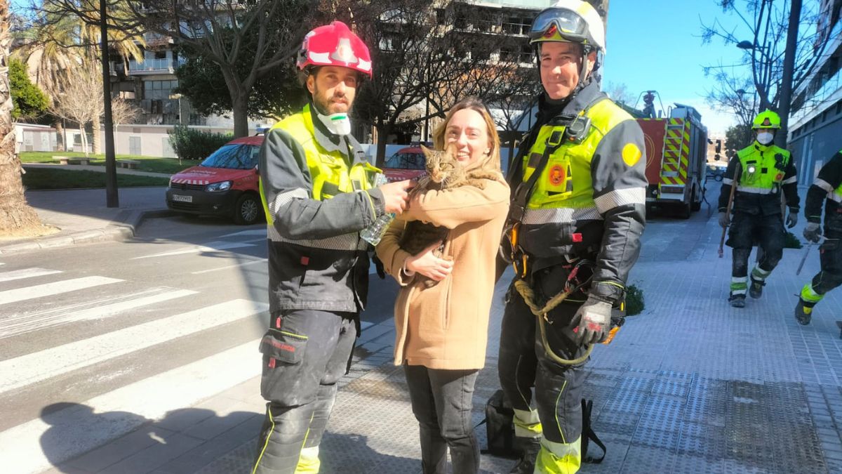 Los bomberos posan junto a Andrea y el gato Coco, al que han rescatado del edificio calcinado del Campanar