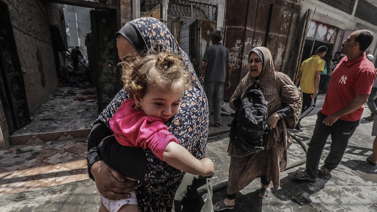 Una mujer palestina sostiene a un niño mientras camina tras el bombardeo israelí de un edificio residencial poblado en Nuseirat