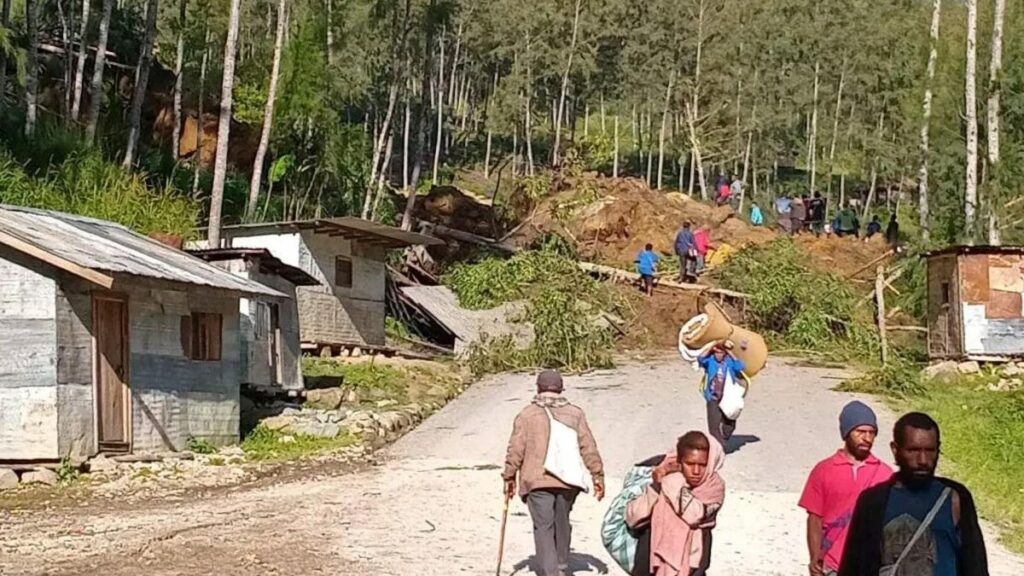 La gente camina con sus pertenencias en la zona donde un deslizamiento de tierra azotó la aldea de Kaokalam, provincia de Enga, Papúa Nueva Guinea, el 24 de mayo de 2024