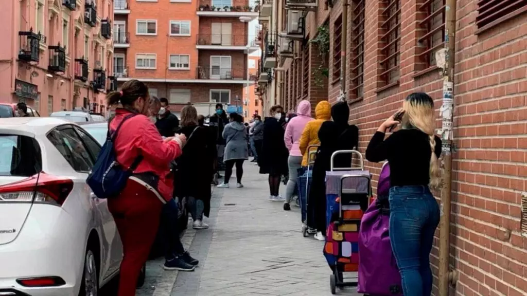 Fila de extranjeros esperando para recoger alimentos en un economato en Madrid.