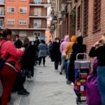 Fila de extranjeros esperando para recoger alimentos en un economato en Madrid.