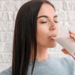 Mujer bebiendo un vaso de leche sin lactosa.