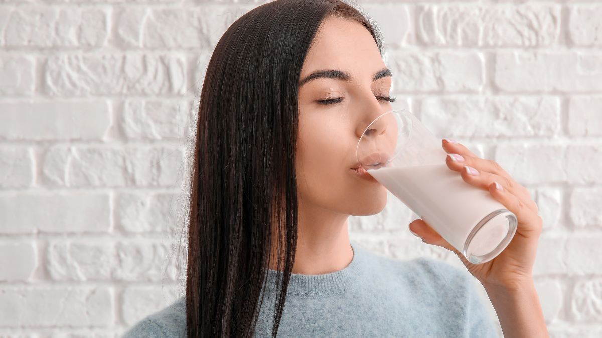 Mujer bebiendo un vaso de leche sin lactosa.