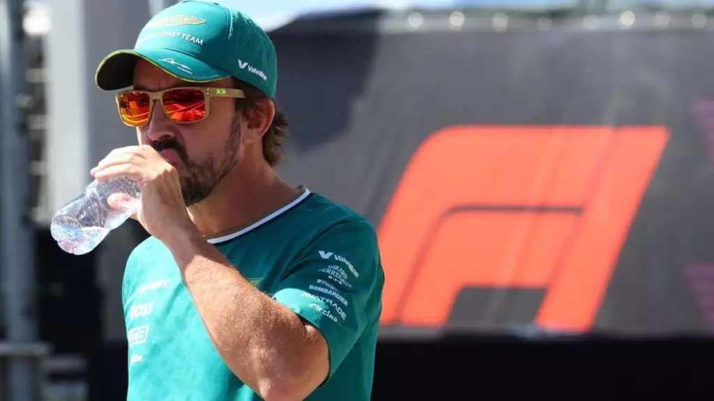 Fernando Alonso, piloto de Aston Martin, bebiendo agua antes de un Gran Premio de Fórmula 1.