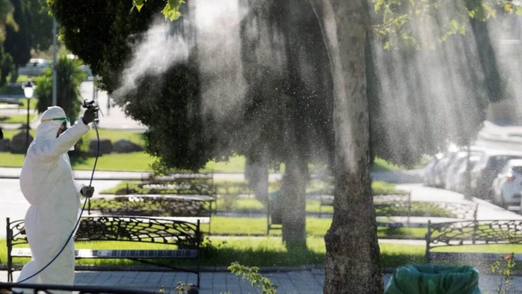 Un operario fumiga unos jardines