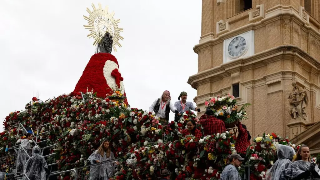 Varias personas colocan las flores a los pies de la Virgen del Pilar durante la tradicional Ofrenda de Flores a la Virgen